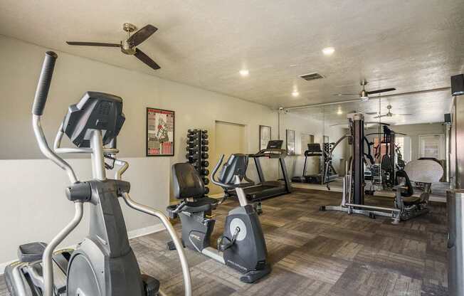 A spacious gym with a variety of equipment including treadmills, stationary bikes, and weight machines.