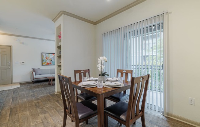 a dining room with a wooden table and chairs and a large window