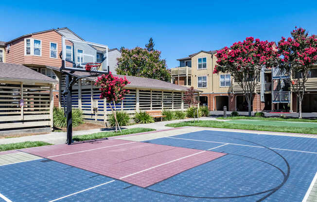 A basketball court in front of apartment buildings.