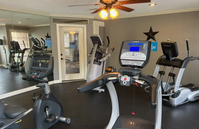 a gym with cardio machines and a ceiling fan