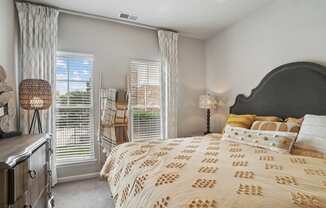 a bedroom with a large bed and two windows