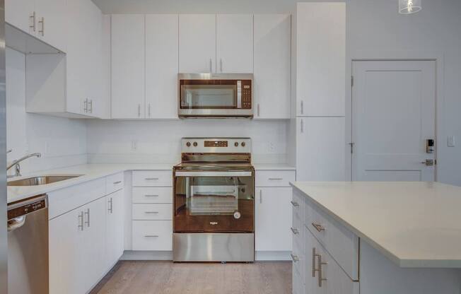 A modern kitchen with white cabinets and stainless steel appliances.