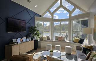 A living room with a large window and a TV on the wall.
