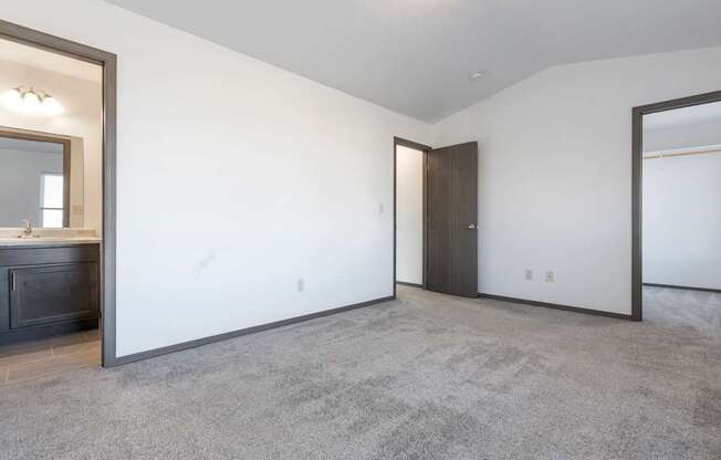 A spacious room with a grey carpet and a wooden door.