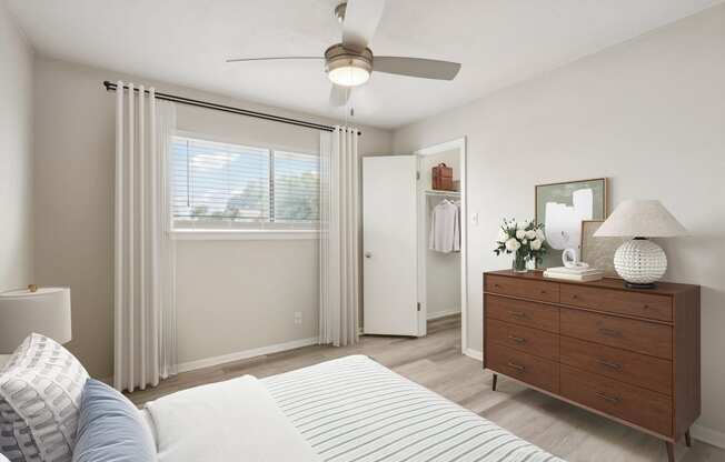 a bedroom with a ceiling fan and a dresser