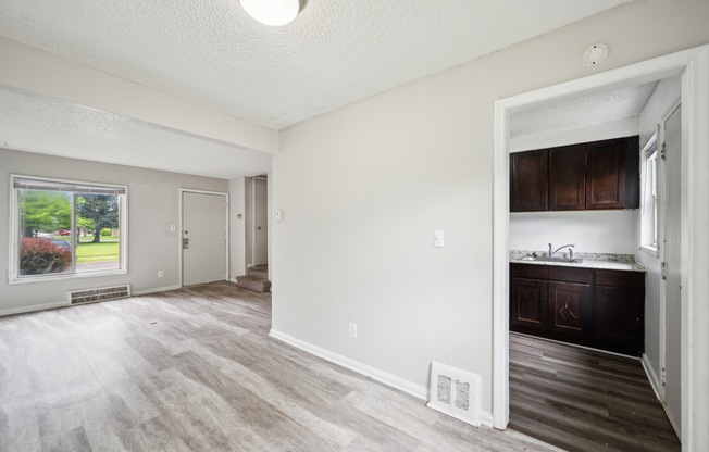 A spacious room with a window, a door, and a wooden floor.