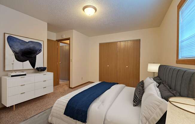 a bedroom with a bed and a dresser. Fargo, ND Kennedy Apartments