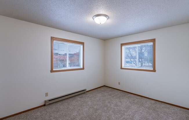 the living room of an empty house with two windows. Fargo, ND West Oak Apartments.