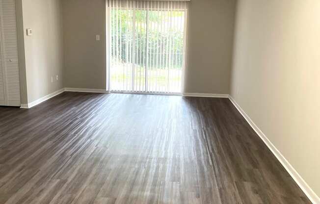 an empty living room with wooden floors and a sliding glass door