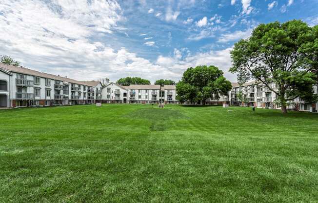 a large green lawn in front of a row of apartment buildings