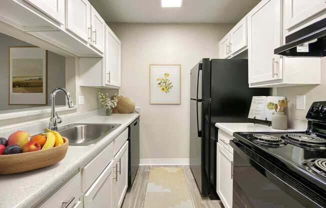 A kitchen with a black refrigerator and white cabinets.