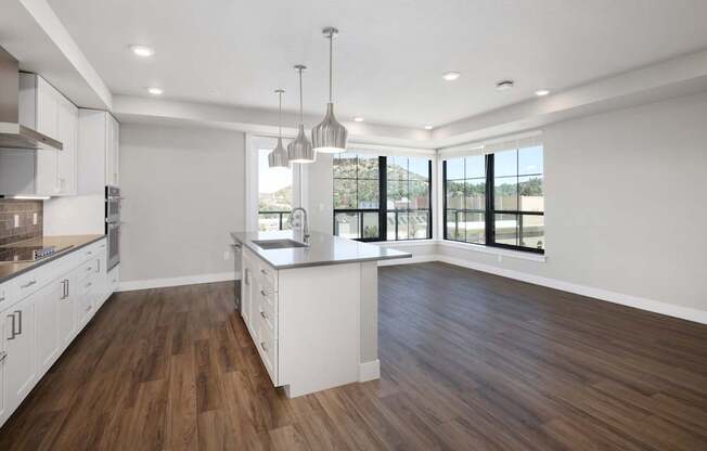 A modern kitchen with wooden floors and white cabinets.