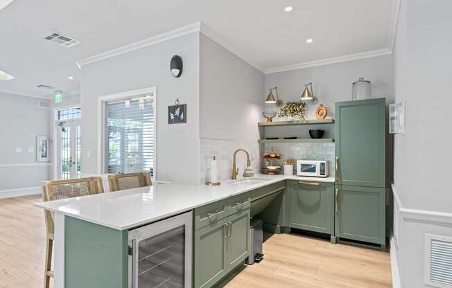 A kitchen with green cabinets and a white island.