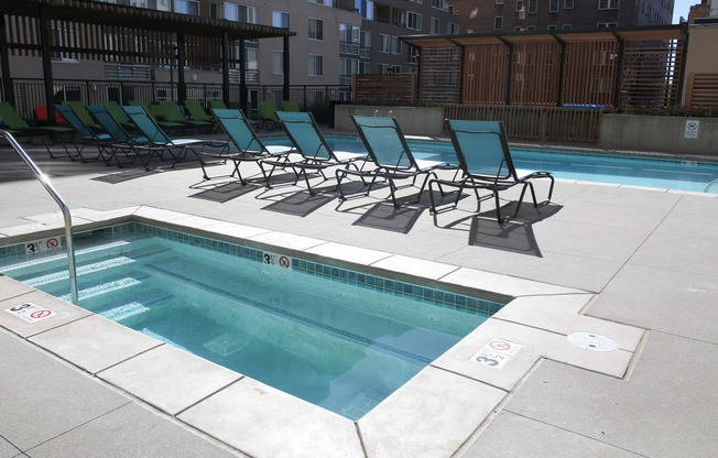 the pool and chaise lounge chairs in the pool area of an apartment building