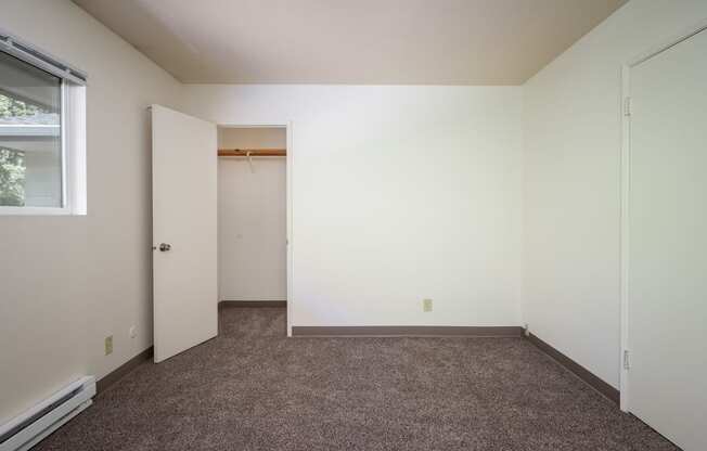 an empty room with carpet and a door to a closet