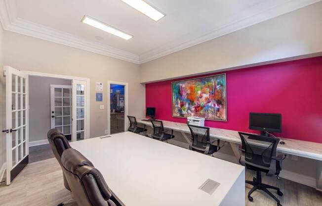 A conference room with a white table and chairs, a pink wall, and a painting on the wall.