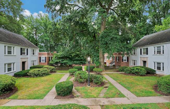 A white house with a black roof is surrounded by greenery.