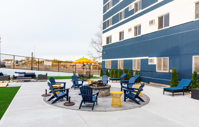 an outdoor patio with chairs and a fire pit next to a building