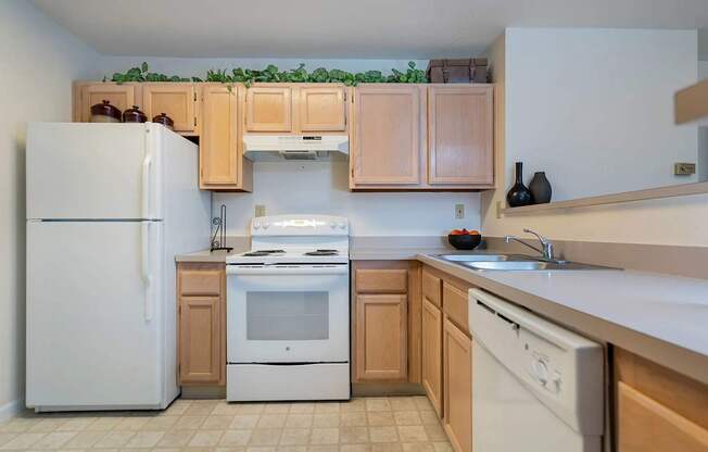 A kitchen with a white refrigerator, white oven, and white dishwasher.at Camden Place, Ohio