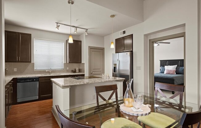 a kitchen and dining room with a bed in the background