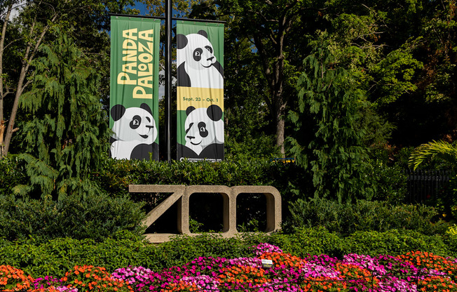 a sign for the zoo in front of some flowers