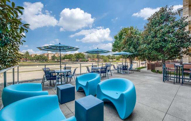 an outdoor patio with blue tables and chairs and umbrellas