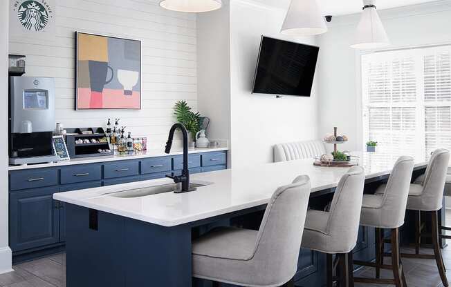 a kitchen with blue cabinets and an island with a sink and chairs