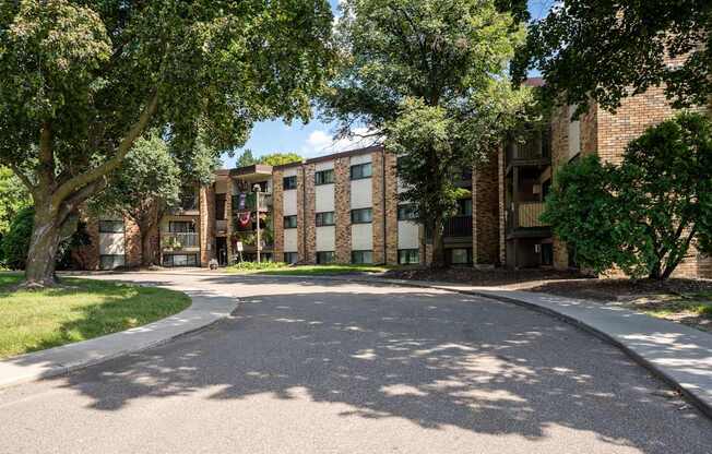 A tree-lined street with a building in the background. White Bear Lake, MN White Bear Terrace Apartments