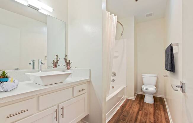a bathroom with white cabinets and a white toilet next to a white bathtub