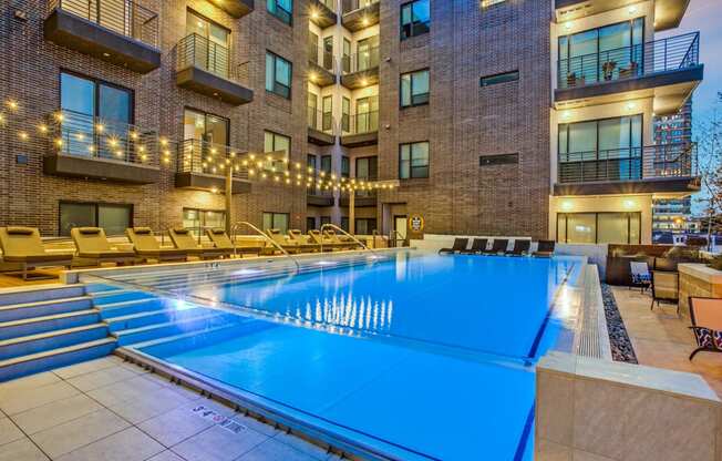 a pool with a blue water feature in front of an apartment building