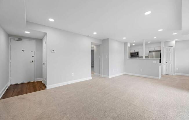 A spacious, empty room with white walls and carpeted floor.