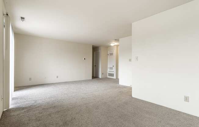 an empty living room with white walls and carpet