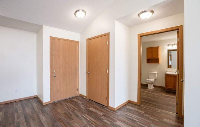 A room with two doors and a bathroom visible through one of the doors. Bismarck, ND Sierra Ridge Apartments