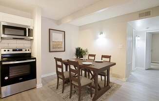 A kitchen with a table and chairs and a fridge.