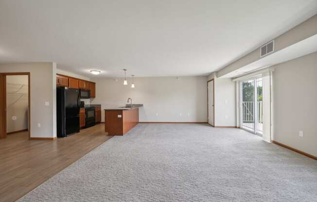 a spacious living room with a kitchen and a sliding glass door