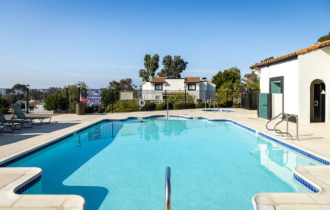 A swimming pool in a residential area with a house and trees in the background.