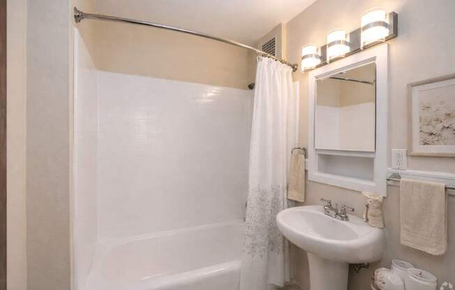 A white bathroom with a white tub, sink, and toilet.