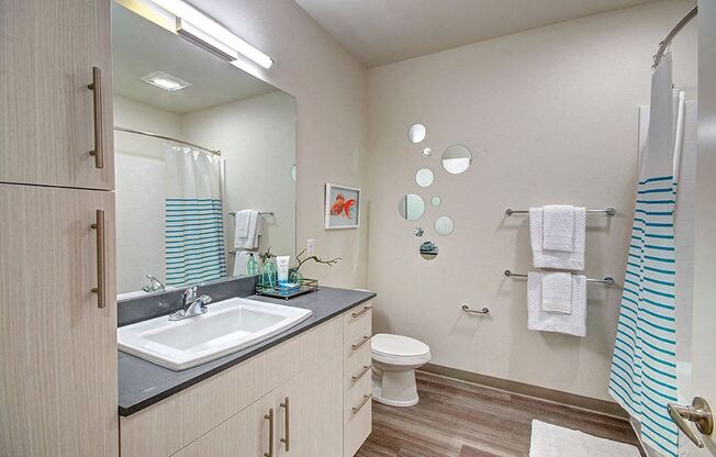 A bathroom with a sink, toilet, and a striped shower curtain. at Ravello Apartments, Redmond, WA
