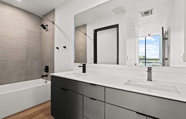A modern bathroom with a white sink and black cabinets.