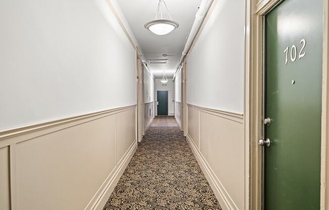 a hallway with a green door and a patterned carpet in a hotel room