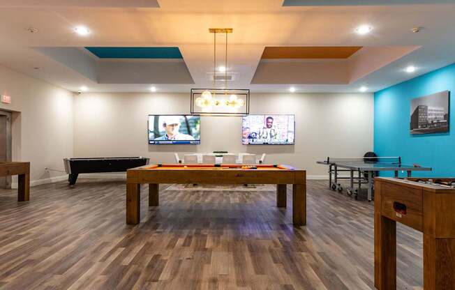 a billiards room with a pool table and televisions