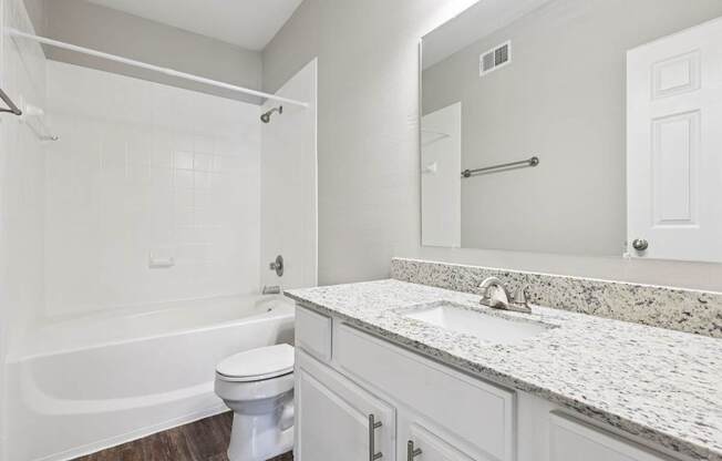 A white bathroom with a tub, toilet and sink.