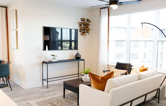 A living room with a white couch, a black coffee table, and a ceiling fan.