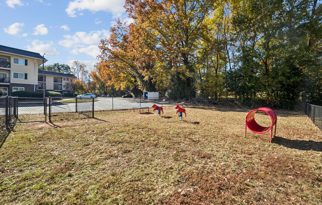 A playground with a red tunnel and two children playing.