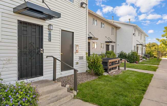 A white house with a black door and a small garden in front.