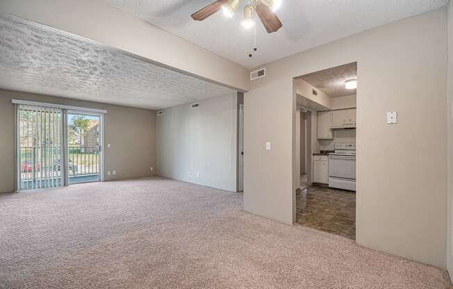 Omaha, NE Evergreen Terrace Apartments. A living room with a ceiling fan and a kitchen in the background