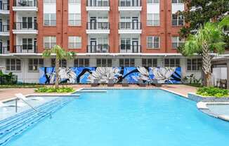 Swimming pool with and lounging chairs at The Grand at Upper Kirby apartments in Houston, TX