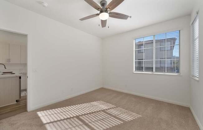 A room with a ceiling fan and a window with blinds.