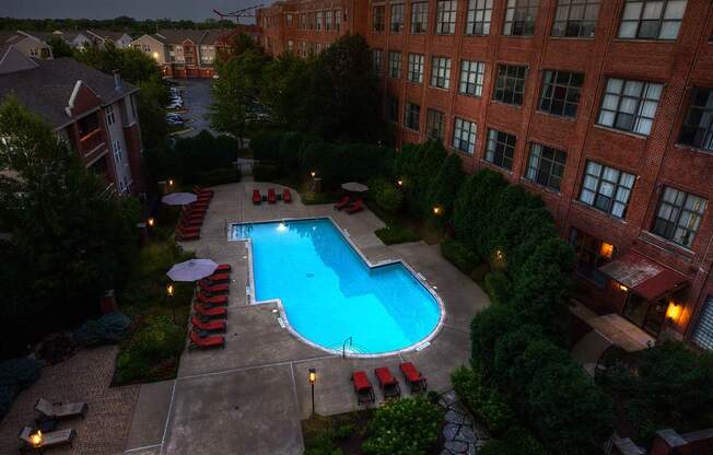 A pool surrounded by a patio with chairs and umbrellas.