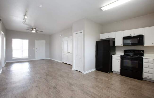 A spacious kitchen with black appliances and white cabinets.